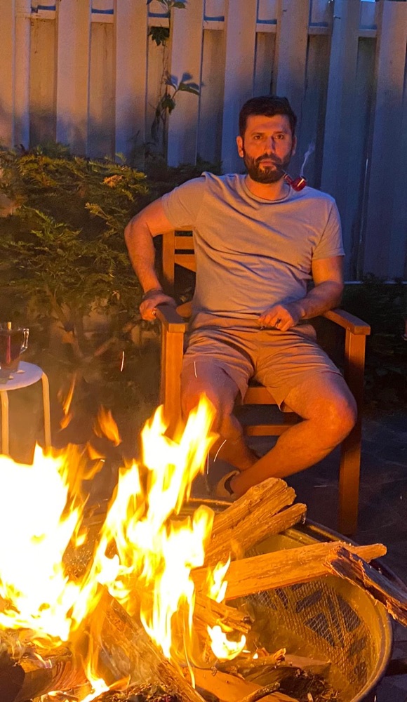 Ogulcan Aydogan relaxing by a fire pit on a summer evening